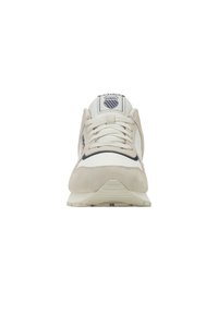 Pohled zepředu na bílo-beige tenisku K-Swiss s bílými tkaničkami a logem značky na jazyku proti bílému pozadí.