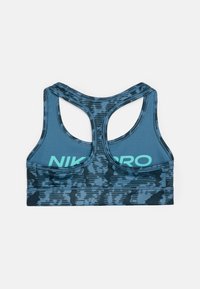 Sportovní podprsenka v námořnické modři s texturovaným, abstraktním vzorem. Design s otevřenými zády a potištěným logem "NIKE PRO" v mátově zelené na zadní straně.
