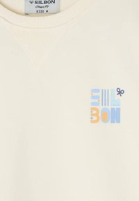 Sudadera color crema con cuello y puños de canalé. Presenta un diseño gráfico multicolor en la parte frontal en tonos azules y naranjas.