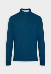 Långärmad pikétröja i mörkblå bomull, med knäppt krage, liten logga på bröstet och ribbade muddar.