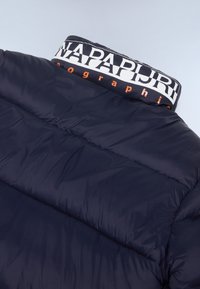Marineblå pufferjakke med høj krave, der har hvidt og orange logo. Glat, polstret tekstur med horisontale syninger.