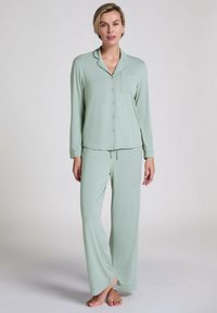 Loungewear-set in zachte mintgroene stof. Bestaat uit een lang mouw overhemd met een zak en broek met een trekkoord en wijde benen.