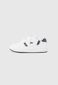 Άσπρα αθλητικά παπούτσια με λουράκια βέλκρο, μαύρο γεωμετρικό σχέδιο και πράσινο κεντημένο λογότυπο. Λαστιχένια σόλα με ελαφριά επιφάνεια πρόσκρουσης.