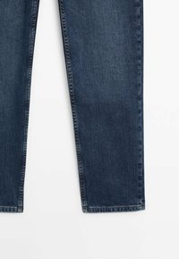 Jean en denim bleu foncé avec une coupe droite, présentant des coutures visibles et des poches latérales standard. Pas d'embellissements ni de motifs.