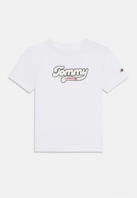 Hvit bomull t-skjorte med "Tommy CLASS OF 1985" i en stilisert design. Korte ermer med logo detaljer på venstre erme.