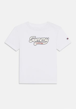 Hvit bomull t-skjorte med "Tommy CLASS OF 1985" i en stilisert design. Korte ermer med logo detaljer på venstre erme.