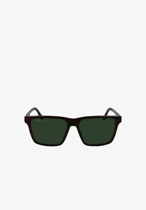 Tortie kvadrātu formas saulesbrilles ar tumši zaļiem stikliem. Uz kreisās tempļa ir Lacoste logo. Plastmasas rāmim ir gluda virsma.