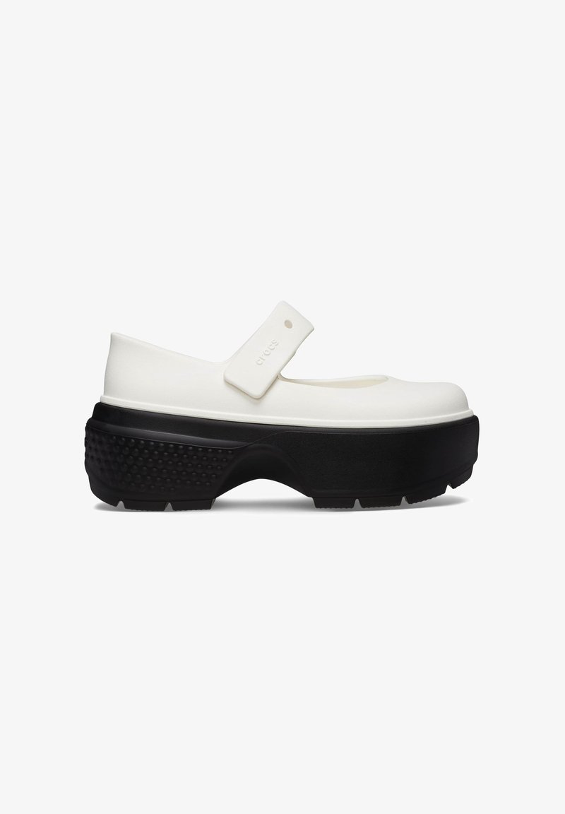 Chaussure blanche de style Mary Jane avec une sangle arrondie, une semelle plate noire et un extérieur en caoutchouc texturé ; conçue pour le confort et la flexibilité.