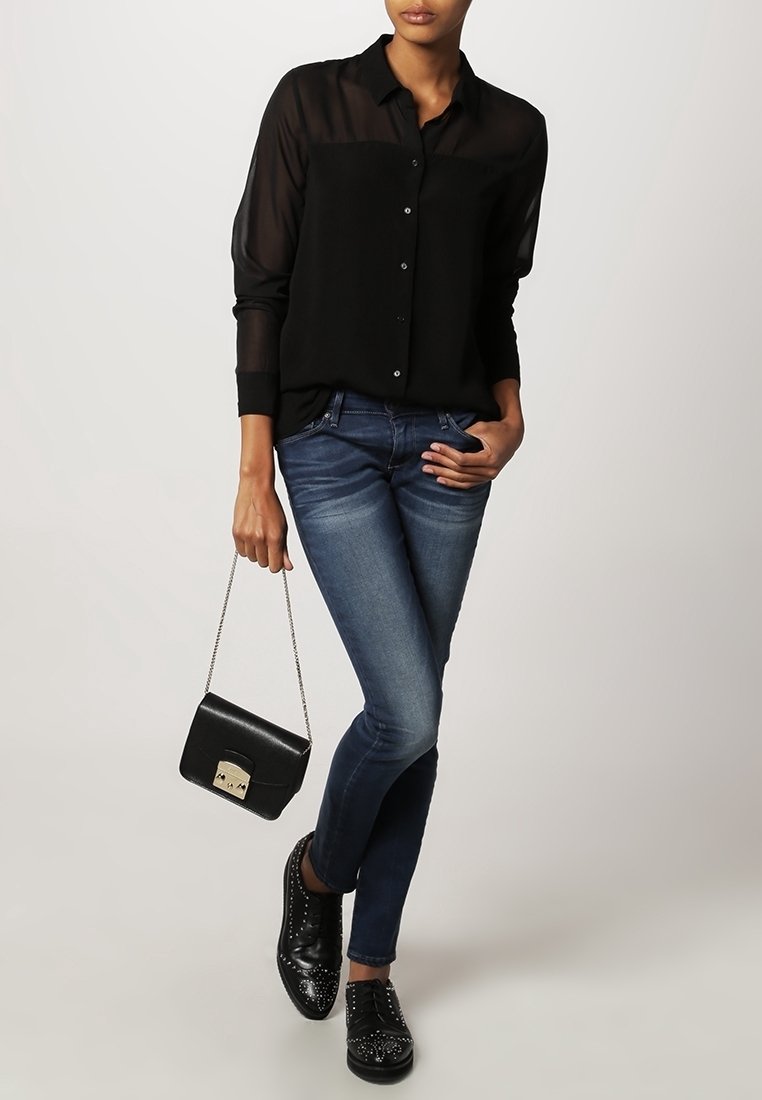 Black semi-sheer button-up shirt, dark blue jeans, black studded sneakers, and a small black handbag with a silver chain strap.