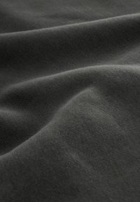 Weicher dunkelgrauer Stoff mit sanften Falten und glatter Textur, der in der Nahaufnahme feine Strickdetails zeigt.