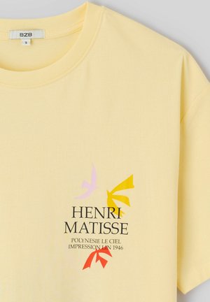 T-shirt jaune clair avec des formes d'oiseaux abstraites colorées et le texte « Henri Matisse Polynésie Le Ciel Impression Lin 1946 » sur la poitrine.