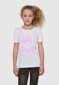 Balta kokvilnas T-krekls ar rozā "GRL PWR" grafiku. Īsām piedurknēm, apaļa kakla izgriezuma un brīvā piegriezumā. Vilkts kopā ar tumšām legingām, radot ikdienišķu izskatu.