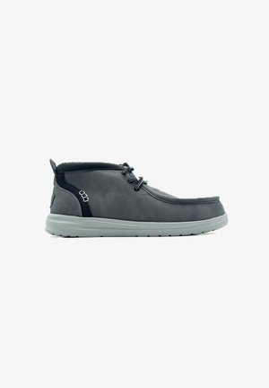 Bota de tobillo de cuero gris con punta redonda, cordones en la parte delantera, detalles en negro y suela flexible de goma gris. Presenta detalles de superficie texturizada.