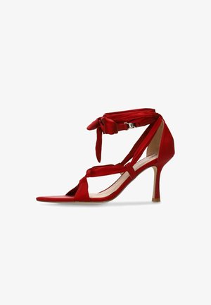 Sandale rouge en satin à talon haut avec attaches à la cheville, talon aiguille fin, bout ouvert et lanières croisées.
