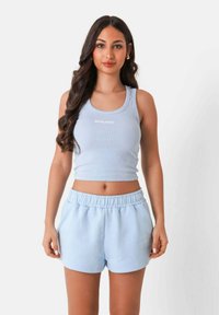 Canottiera a coste blu chiaro con logo bianco, abbinata a pantaloni corti morbidi coordinati con vita elastica e tasche laterali.