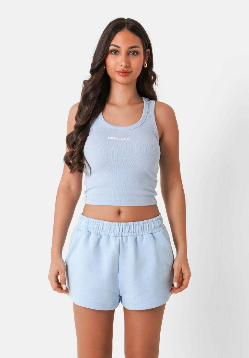 Canottiera a coste blu chiaro con logo bianco, abbinata a pantaloni corti morbidi coordinati con vita elastica e tasche laterali.