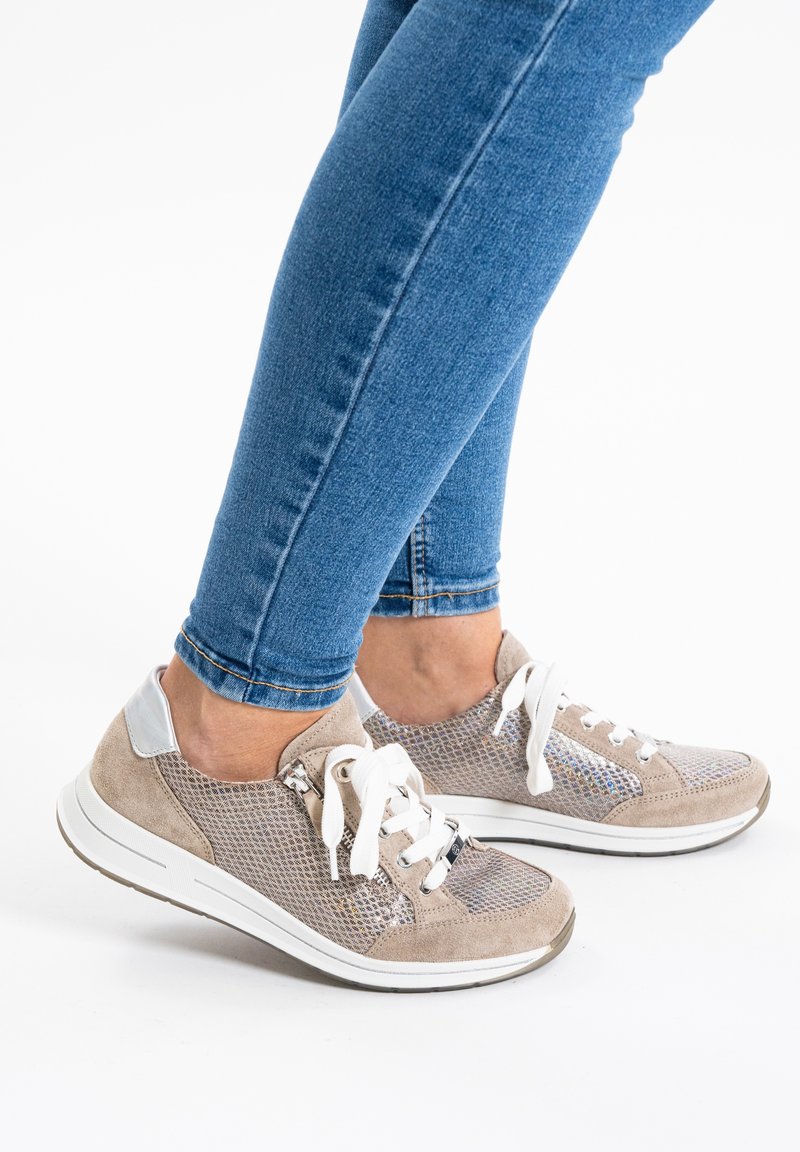 Helle graue Sneakers mit Netzpaneelen, Wildlederakzenten, weißen Schnürsenkeln und einer gepolsterten Sohle, kombiniert mit schmal geschnittenen blauen Jeans.