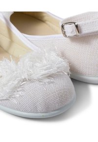 Ballerine bianche con tessuto testurizzato, caratterizzate da un accentuazione soffice e trasparente sulla punta e una fibbia argentata sulla cinghia. Suole in gomma.