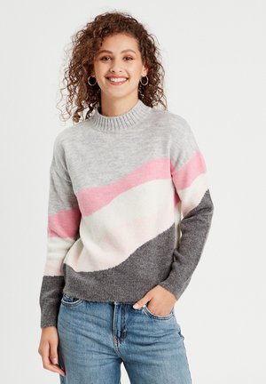 Suéter de punto acogedor con base gris y bandas onduladas en rosa y blanco, cuello acanalado y textura suave. Combinado con jeans de mezclilla.