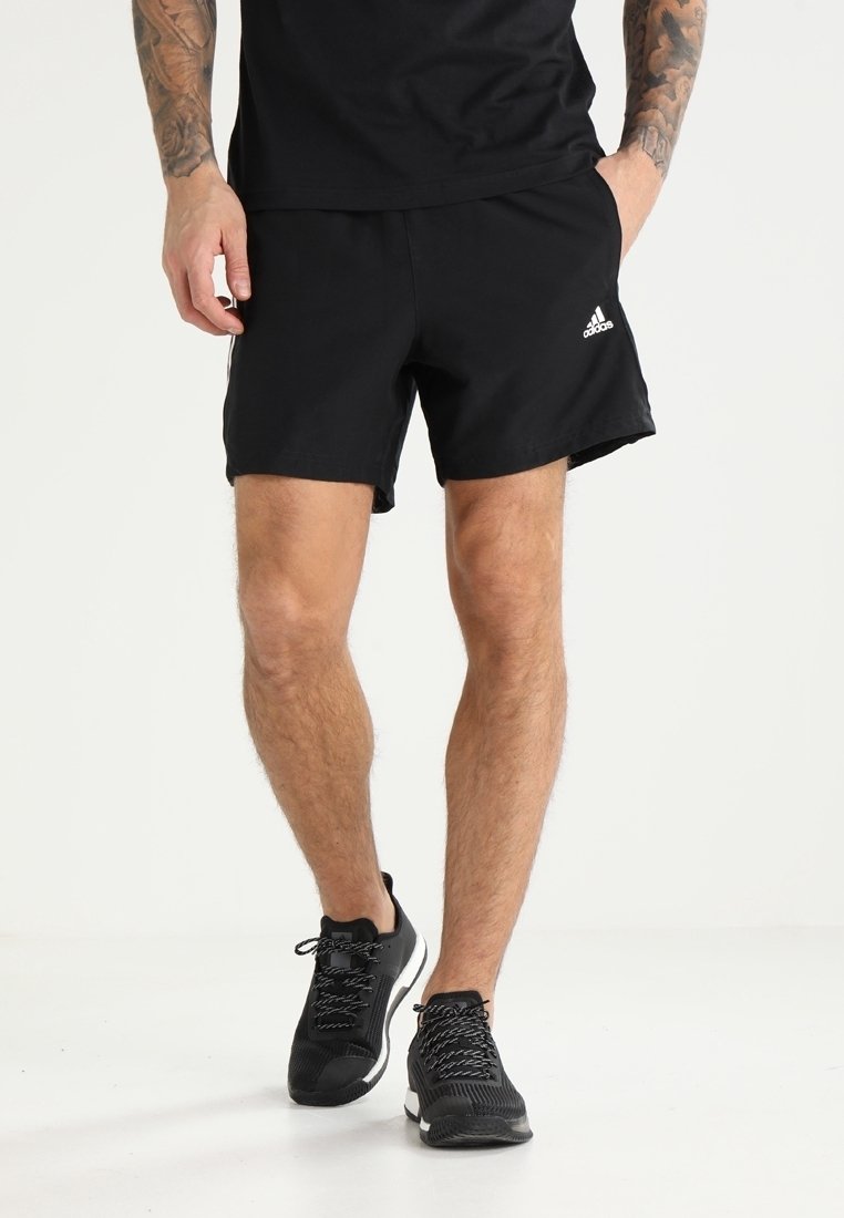 Mustat urheilushortsit, joissa on kevyt kangas, joustava vyötärö ja Adidas-logo oikeassa alakulmassa, yhdistettynä mustiin lenkkikenkiin.
