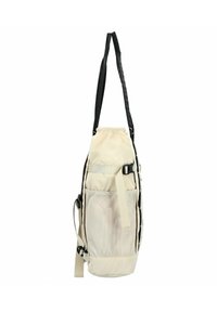 Zaino in tessuto beige con spallacci neri, una tasca laterale in rete, fondo piatto e chiusura regolabile. Presenta un design elegante e angolato.