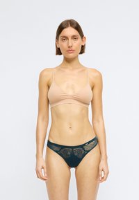 Lehce polstrovaný nahý bralet s nastavitelnými ramínky, spárovaný s tmavozelenými kalhotkami zdobenými krajkou a síťovinou s puntíky.