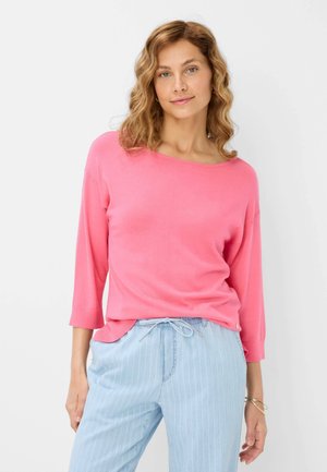 Roze, langmouwtop met een wijde halslijn en een ontspannen pasvorm. De stof lijkt zacht met een gladde textuur, gecombineerd met lichtblauwe gestreepte broek.