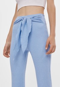 Ribbat ljusblå byxor med ett frontband och en figurnära design, i ett texturerat tyg och med utsvängda benöppningar.