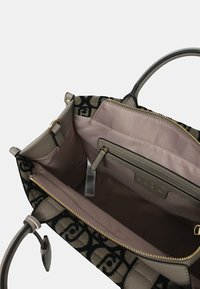 Borsa a tracolla nera e beige con esterno testurizzato e rivestimento in tessuto morbido. Presenta una chiusura con zip, una tasca interna con zip e dettagli del logo.