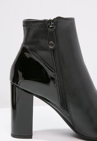 Czarne botki za kostkę na grubym wysokim obcasie, z bocznym zamkiem błyskawicznym oraz połączeniem matowej i błyszczącej skóry.