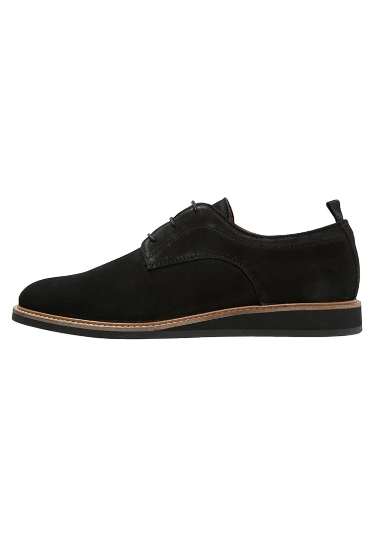 Scarpe da uomo eleganti in suede nero con rifiniture marroni sulla suola e linguetta sul tallone, mostrate in profilo laterale su sfondo bianco.