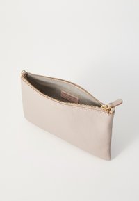 Borsetta in pelle rosa chiaro con finitura testurizzata, zip dorata e etichetta interna con il marchio. Forma compatta e rettangolare senza motivi visibili.