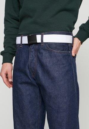 Denim jeans in dark blue with a relaxed fit, featuring orange stitching and a white elastic belt with a black metal buckle.