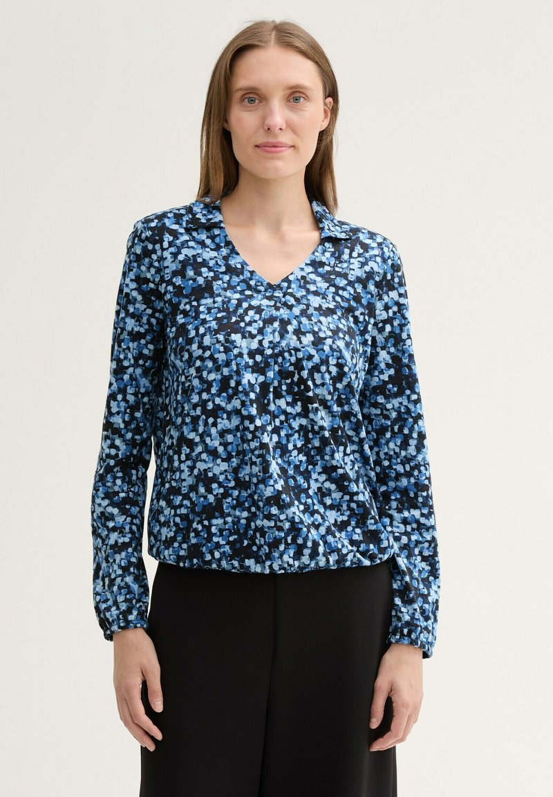 Blaue und schwarze gemusterte Bluse mit V-Ausschnitt, langen Ärmeln und einer lockeren Passform. Sie zeichnet sich durch eine Mischung aus hellblauen und dunkelblauen Formen aus.