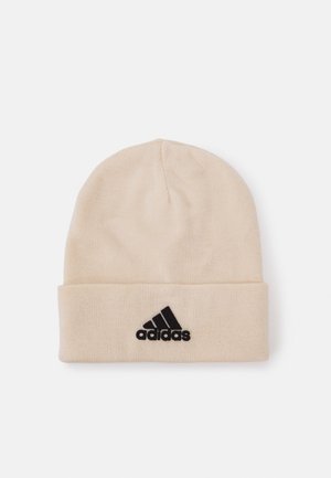 Gorro de punto beige con un dobladillo, presenta un logo negro de Adidas en la parte delantera; textura suave, ajuste ceñido y diseño ligero.