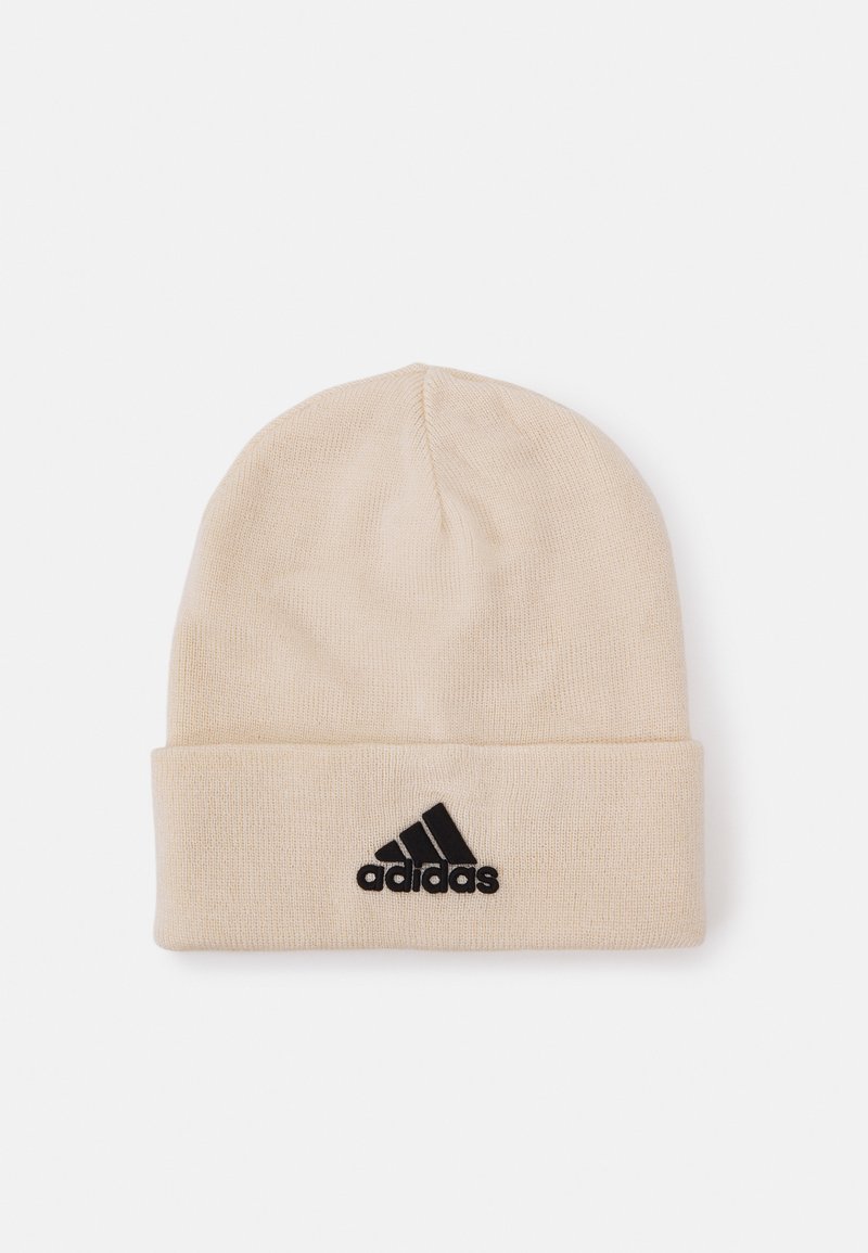 Gorro de punto beige con un dobladillo, presenta un logo negro de Adidas en la parte delantera; textura suave, ajuste ceñido y diseño ligero.