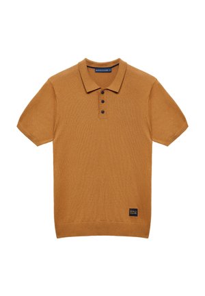 Herrenshirt in Kurzarm, kamelebraun, mit drei schwarzen Knöpfen und einem kleinen "Polo Club"-Etikett nahe dem Saum.