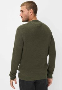 Maglione verde scuro realizzato in tessuto lavorato a maglia. Presenta un colletto rotondo, maniche lunghe e una vestibilità leggermente svasata in vita.