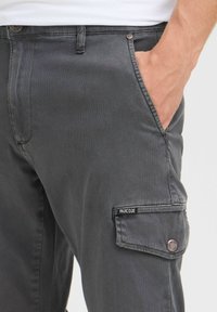 Szare spodnie cargo o slim fit, z bocznymi kieszeniami, łatą z logo i gładką bawełnianą teksturą. Metalowe zapięcie na guzik w pasie.