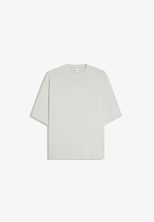 T-shirt oversize grigio chiaro manica corta con scollatura tonda, stesa su fondo bianco.