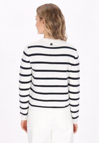 White and navy striped sweater with a round neck and long sleeves. Features a small black button detail at the back neck. Soft and textured material.