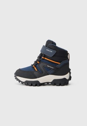 Botte de randonnée enfant bleu marine et noire avec des accents orange, semelle robuste, bride velcro étiquetée "GEOX" et marquage "AMPHIBIOX" sur le côté.