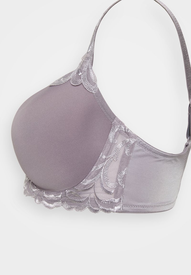 Szary stanik z gładkiego materiału, ozdobiony koronką z falbaniastymi brzegami oraz regulowanymi ramiączkami. Miseczki mają zaokrąglony kształt i subtelną fakturę.