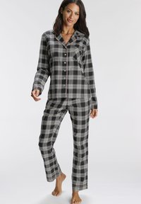 Black and white plaid pajama set features button-up top with a pocket, long sleeves, and matching pants with red accents at the hem.