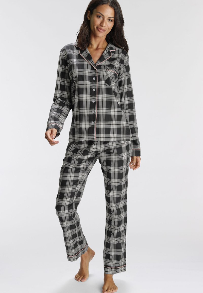 Black and white plaid pajama set features button-up top with a pocket, long sleeves, and matching pants with red accents at the hem.