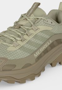 Gros plan d'une chaussure de randonnée Merrell beige avec tissu texturé, laçage renforcé et semelle robuste pour une utilisation en extérieur.