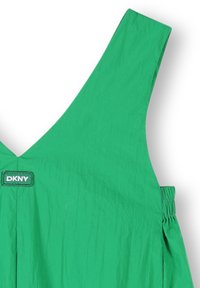 Abito verde con scollo a V, spalline larghe e dettagli elastici sui lati. Patch del logo DKNY vicino allo scollo. Tessuto leggero.