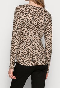 Beige a černý vršek s leopardím potiskem, dlouhý rukáv, měkká textura a volný střih, kulatý výstřih a boční rozparky.