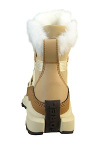 Jasnobrązowy skórzany but z białym futerkiem wykończonym przy kołnierzu, brązowym akcentem na pięcie i czarną naszywką z logo na pięcie. Wzmocnione detale szwów.