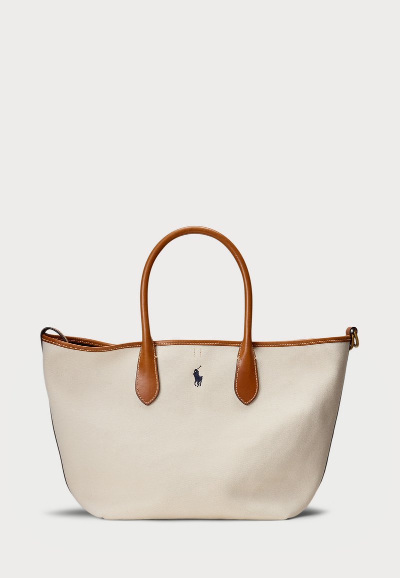 Kanvas torba v kremni barvi z rjavimi usnjenimi detajli in ročaji. Ima modri logotip spredaj, strukturirano obliko in odprt vrh.